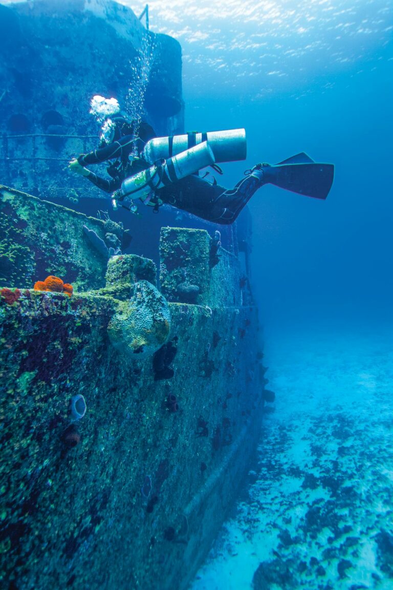 Scuba diver explores a colorful sunken shipwreck in vibrant Mexican waters. Perfect for marine enthusiasts.